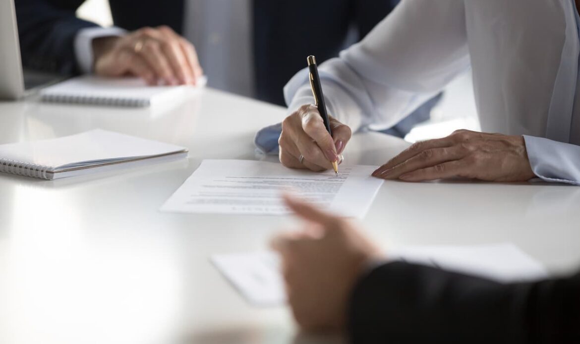 Person som signerar juridiskt dokument under möte – representerar processen för att skriva, bevittna och certifiera en bankfullmakt för användning i Sverige eller utomlands.