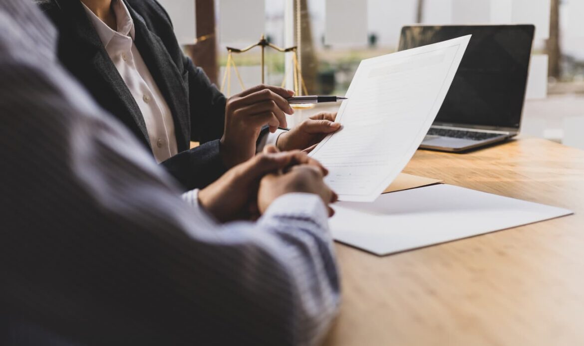 Två personer granskar och diskuterar ett juridiskt dokument – symboliserar processen för att upprätta, bevittna och legalisera en framtidsfullmakt för ekonomiska och personliga angelägenheter.