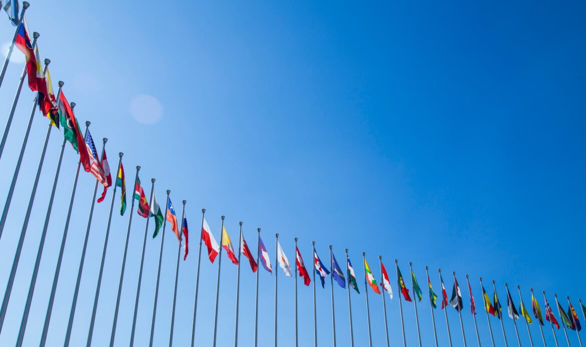 Flera nationella flaggor på rad mot blå himmel som symboliserar internationellt samarbete och de länder som kräver Apostille-stämpel enligt Haagkonventionen.