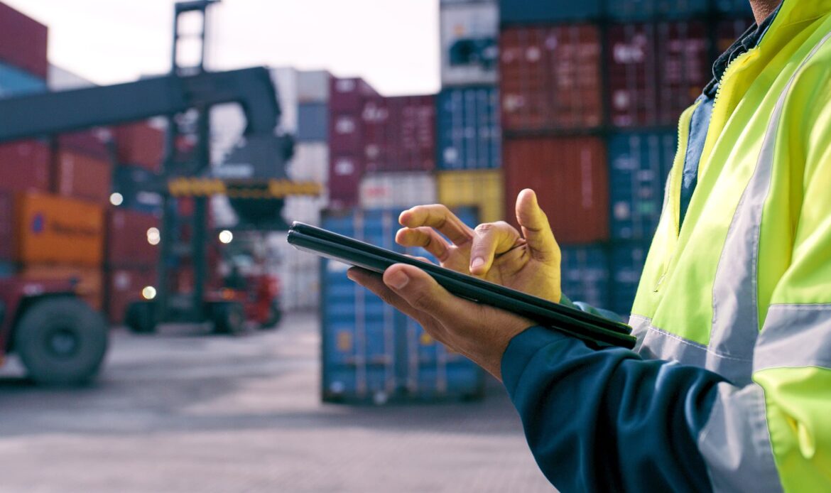 Logistikpersonal med digital surfplatta framför containrar – export och handelsdokument som kräver Apostille vs legalisering.